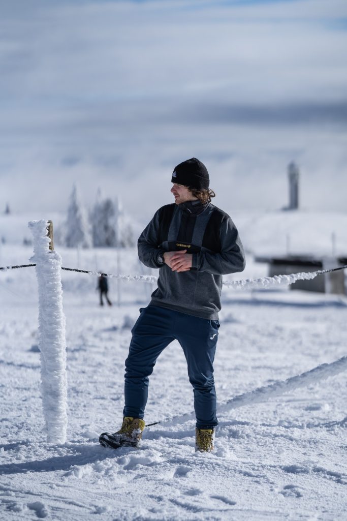 Mann steht auf einem verschneiten Berg